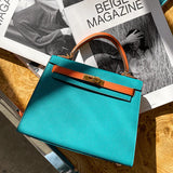 De Jovienne Luxe Teal & Tan Leren Handtas van Liora The Label rust op een houten tafel met een open tijdschrift erachter, zonlicht werpt elegante schaduwen over haar iconische elegantie en tijdloos ontwerp.