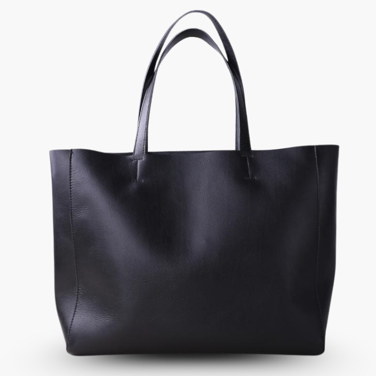 De Emma zwarte leren tote bag van Liora The Label is een ruime en veelzijdige handtas met twee hengsels, gemaakt van echt leer en stijlvol rechtopstaand tegen een witte achtergrond.