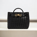 De Alyn zwarte geweven midi leren tote bag van Liora The Label, met korte handgreep en goudkleurige sluiting, straalt moeiteloze elegantie en tijdloze aantrekkingskracht uit. Perfect als luxe handtas voor dames, gepresenteerd tegen een lichte achtergrond.