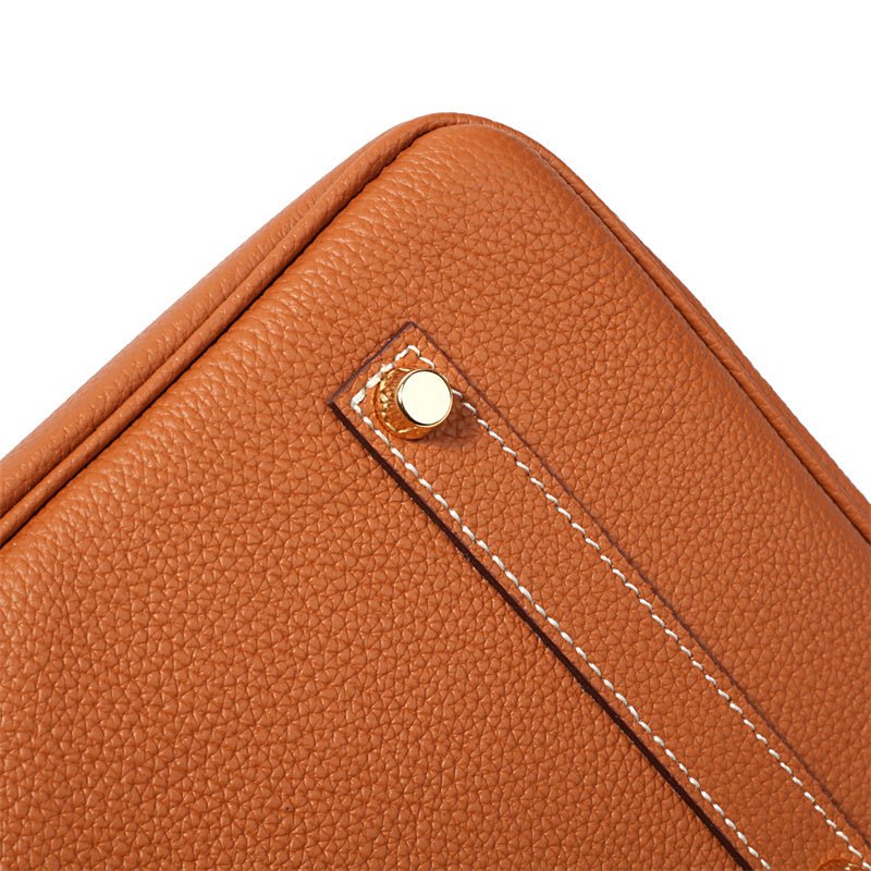 Close-up van de Isla Tan Textured Leather Handtas van Liora The Label, met bruin structuurleer, witte stiksels en een gouden klinknagel detail - tijdloos ontwerp van Klassiek & Tijdloos.