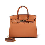 De Isla | Tan Textured Leather Handtas van Liora The Label, met bovenhengsels, goudkleurige hardware en een afneembare bijpassende schouderriem, is ervoor geplaatst.
