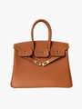 De Isla Tan Textured Leather Handtas van Liora The Label heeft dubbele handvatten, witte stiksels en goudkleurige hardware met slot en sluitingen. Weergegeven op een witte achtergrond voegt deze tas tijdloze elegantie toe aan elke look.