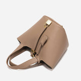 De Elaris Luxe Taupe Leren Emmer Tas van Liora The Label heeft premium structuurleer, gouden hardware, dubbele handgrepen, een gestructureerd ontwerp en een slotdetail aan de voorkant, afgebeeld tegen een witte achtergrond.