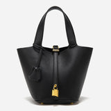 De Elaris Luxe Taupe Leren Emmer Tas van Liora The Label heeft eersteklas structuurleer, twee handgrepen, een goudkleurige hangslotsluiting en een bijpassende leren sleutelhouder-elegant weergegeven tegen een effen witte achtergrond.