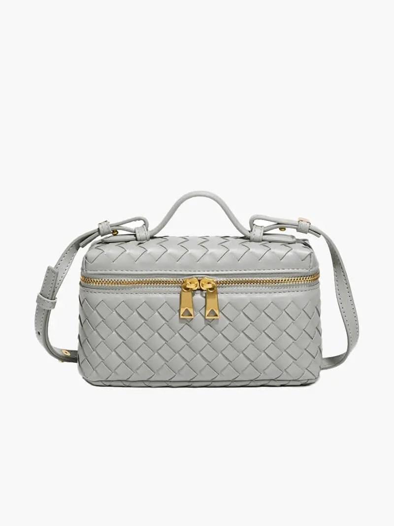 De Luxe Geweven Box Bag van Liora The Label is een kleine, rechthoekige, donkerbruine crossbody van veganistisch leer met gouden ritssluiting, gouden hardware, handvat aan de bovenkant en verstelbare schouderriem.