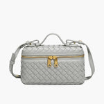 De Luxe Geweven Box Bag van Liora The Label is een kleine, rechthoekige, donkerbruine crossbody van veganistisch leer met gouden ritssluiting, gouden hardware, handvat aan de bovenkant en verstelbare schouderriem.