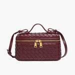De Luxe Geweven Box Bag van Liora The Label is een elegante donkerbruine crossbody met een gouden ritssluiting, bovenhandgreep en verstelbare schouderriem, afgebeeld op een witte achtergrond.