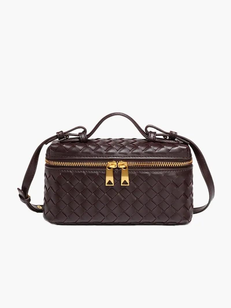 De Luxe Geweven Box Bag van Liora The Label is een elegante, donkerbruine crossbody tas van vegan leer met gevlochten design, goudkleurige ritssluiting met dubbele trekker, bovenhandgreep en verstelbare schouderriem.
