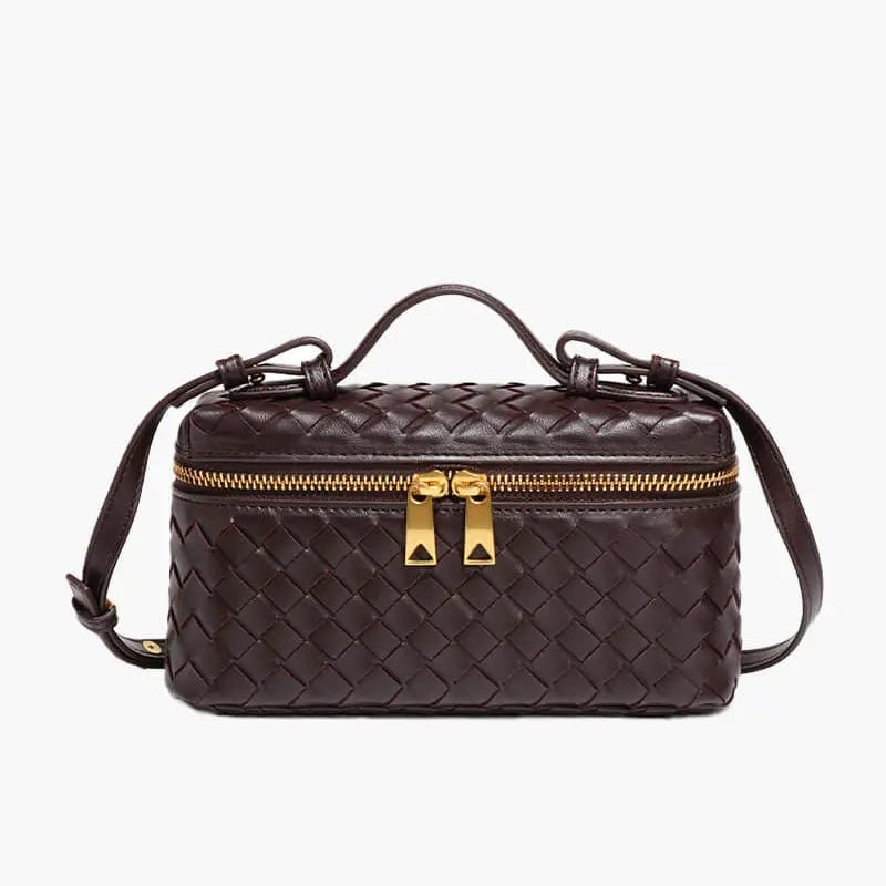 De Luxe Geweven Box Bag van Liora The Label is een elegante, donkerbruine crossbody tas van vegan leer met gevlochten design, goudkleurige ritssluiting met dubbele trekker, bovenhandgreep en verstelbare schouderriem.